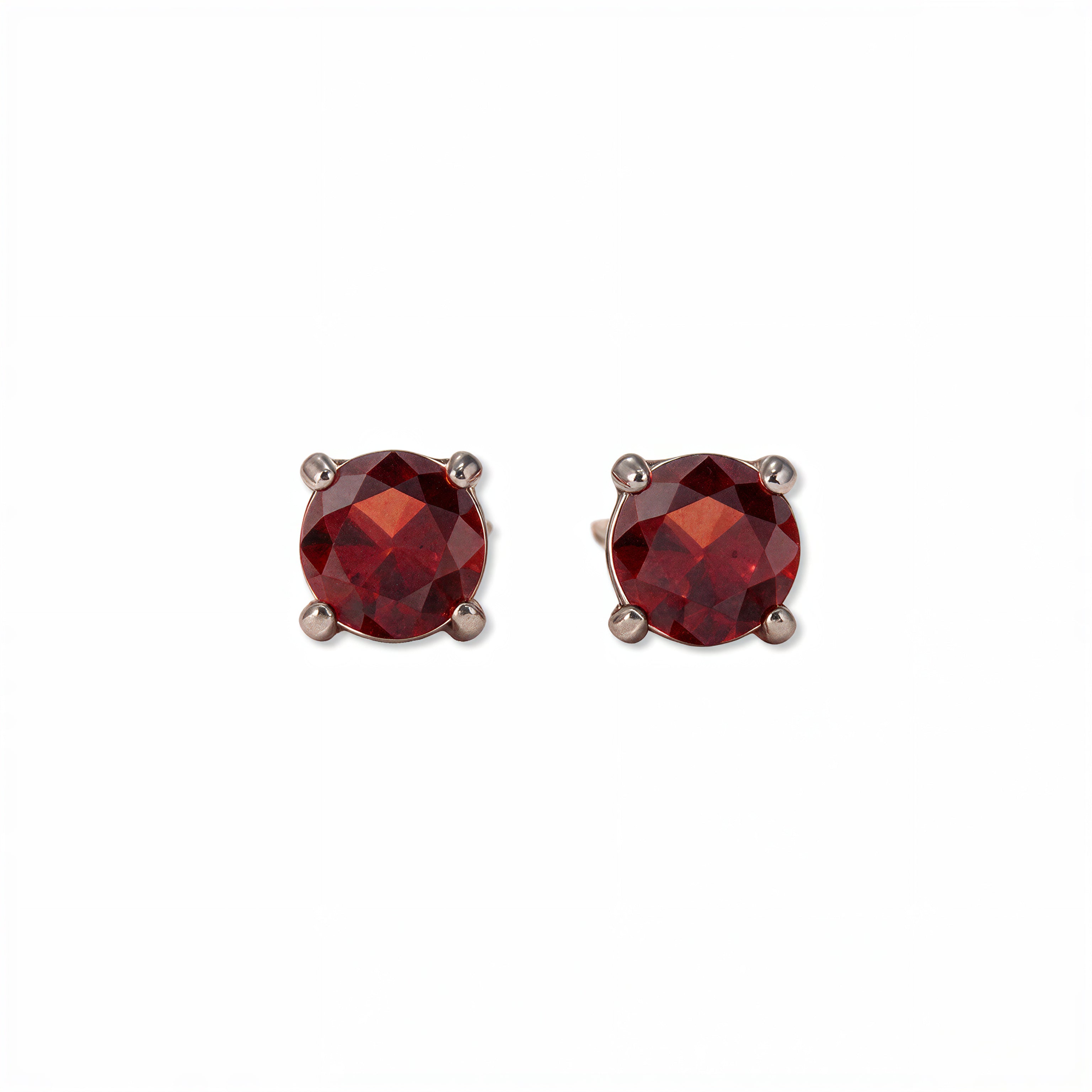 A pair of January Birthstone Round Garnet Cubic Zirconia Stud Earrings by Skōsh Jewelry, featuring faceted deep red round stones in a four-prong sterling silver setting, displayed against a white background.
