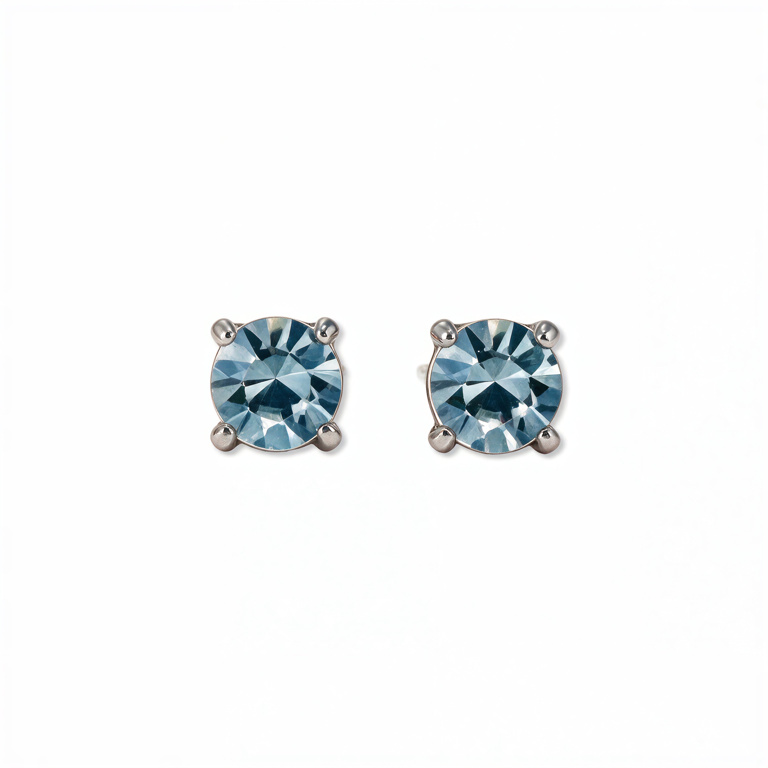 A pair of March Birthstone Round Light Sapphire Cubic Zirconia Stud Earrings by Skōsh Jewelry, featuring faceted light blue round stones in a four-prong sterling silver setting, displayed against a white background.