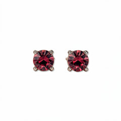 A pair of July Birthstone Round Ruby Cubic Zirconia Stud Earrings by Skōsh Jewelry, featuring faceted red round stones in a four-prong sterling silver setting, displayed against a white background.