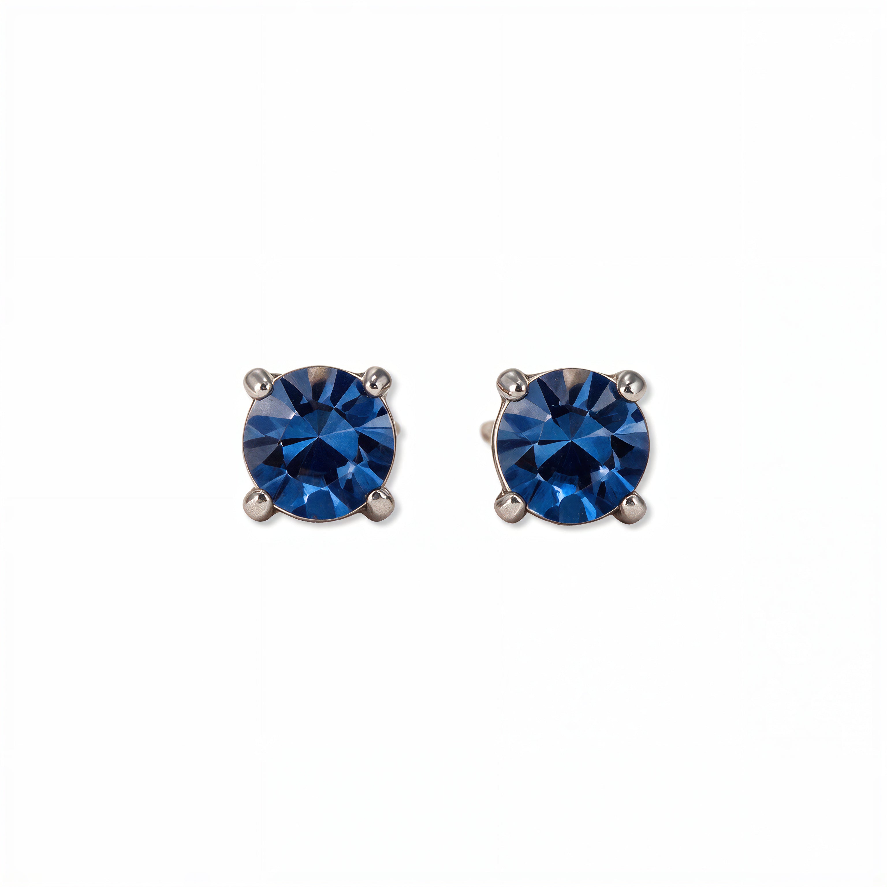 A pair of September Birthstone Round Sapphire Cubic Zirconia Stud Earrings by Skōsh Jewelry, featuring faceted deep blue round stones in a four-prong sterling silver setting, displayed against a white background.