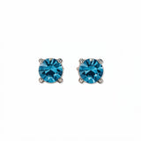 A pair of December Birthstone Round Aqua Cubic Zirconia Stud Earrings by Skōsh Jewelry, featuring faceted blue round stones in a four-prong sterling silver setting, displayed against a white background.