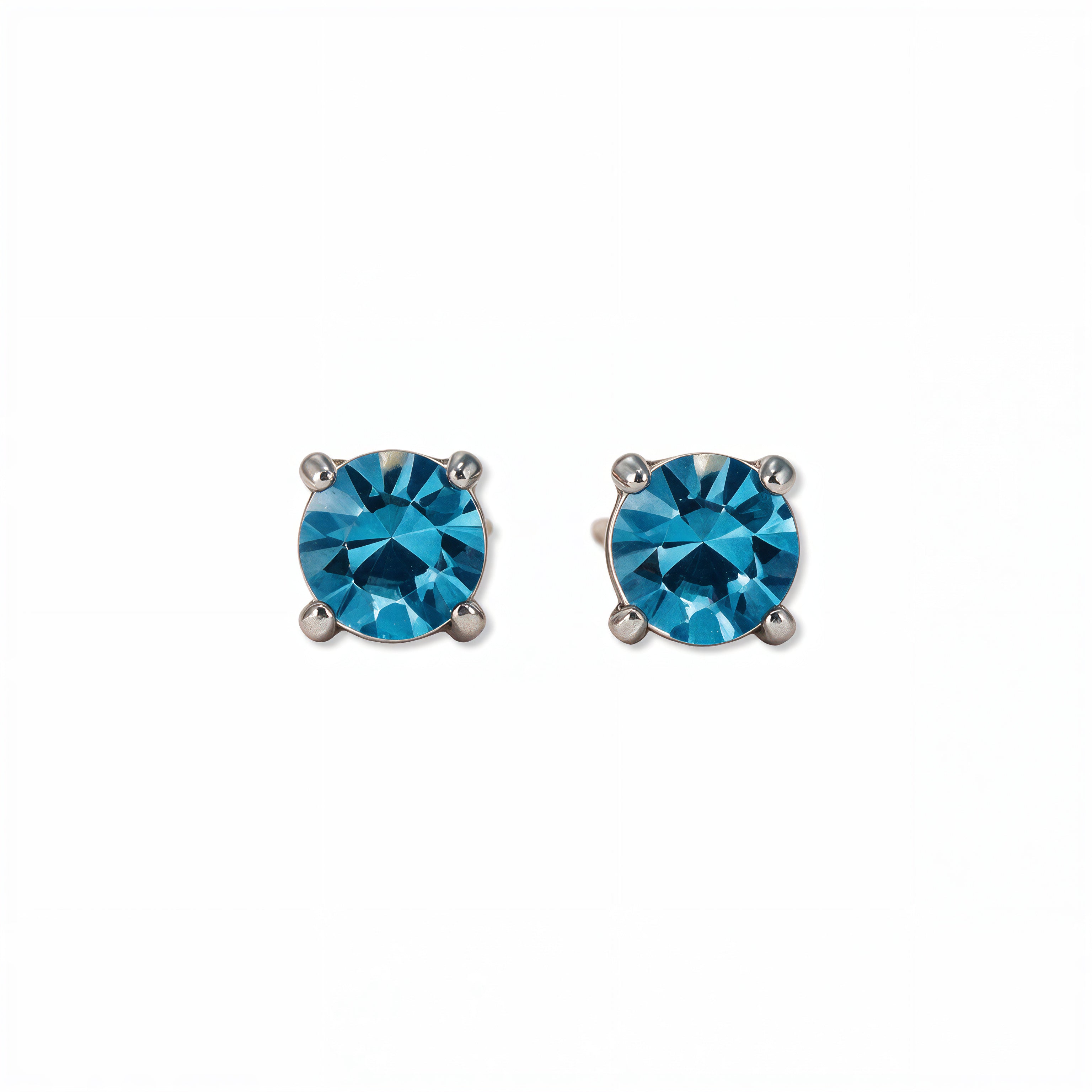 A pair of December Birthstone Round Aqua Cubic Zirconia Stud Earrings by Skōsh Jewelry, featuring faceted blue round stones in a four-prong sterling silver setting, displayed against a white background.