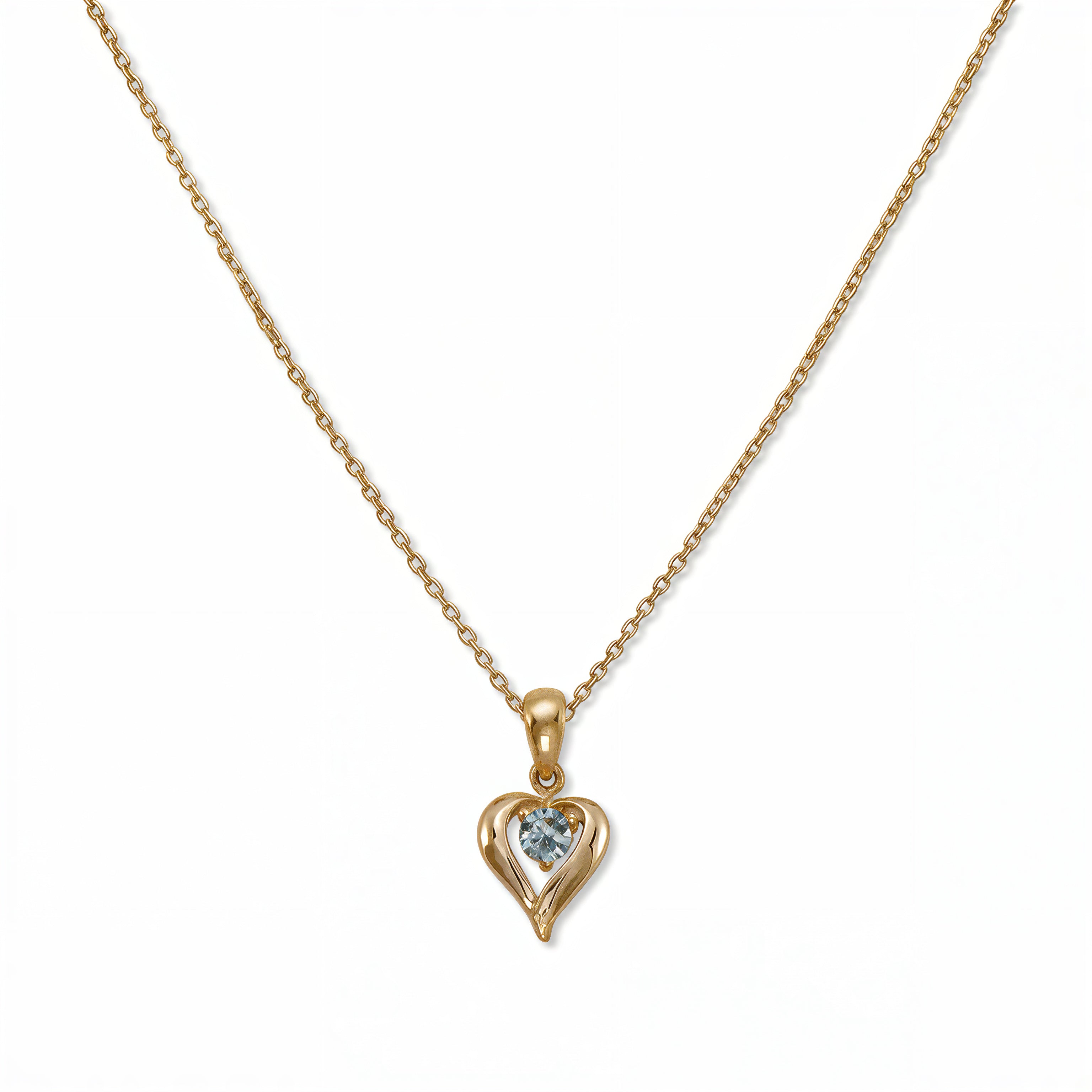 A March Birthstone Light Sapphire Cubic Zirconia Heart Necklace by Skōsh Jewelry, featuring a heart-shaped light blue stone framed in a sculpted gold heart pendant on a fine chain, displayed against a white background.