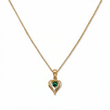 A May Birthstone Emerald Cubic Zirconia Heart Necklace by Skōsh Jewelry, featuring a heart-shaped green stone framed in a sculpted gold heart pendant on a fine chain, displayed against a white background.