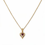 A July Birthstone Ruby Cubic Zirconia Heart Necklace by Skōsh Jewelry, featuring a heart-shaped red stone framed in a sculpted gold heart pendant on a fine chain, displayed against a white background.