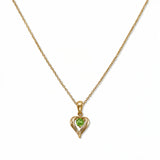 An August Birthstone Peridot Cubic Zirconia Heart Necklace by Skōsh Jewelry, featuring a heart-shaped light green stone framed in a sculpted gold heart pendant on a fine chain, displayed against a white background.