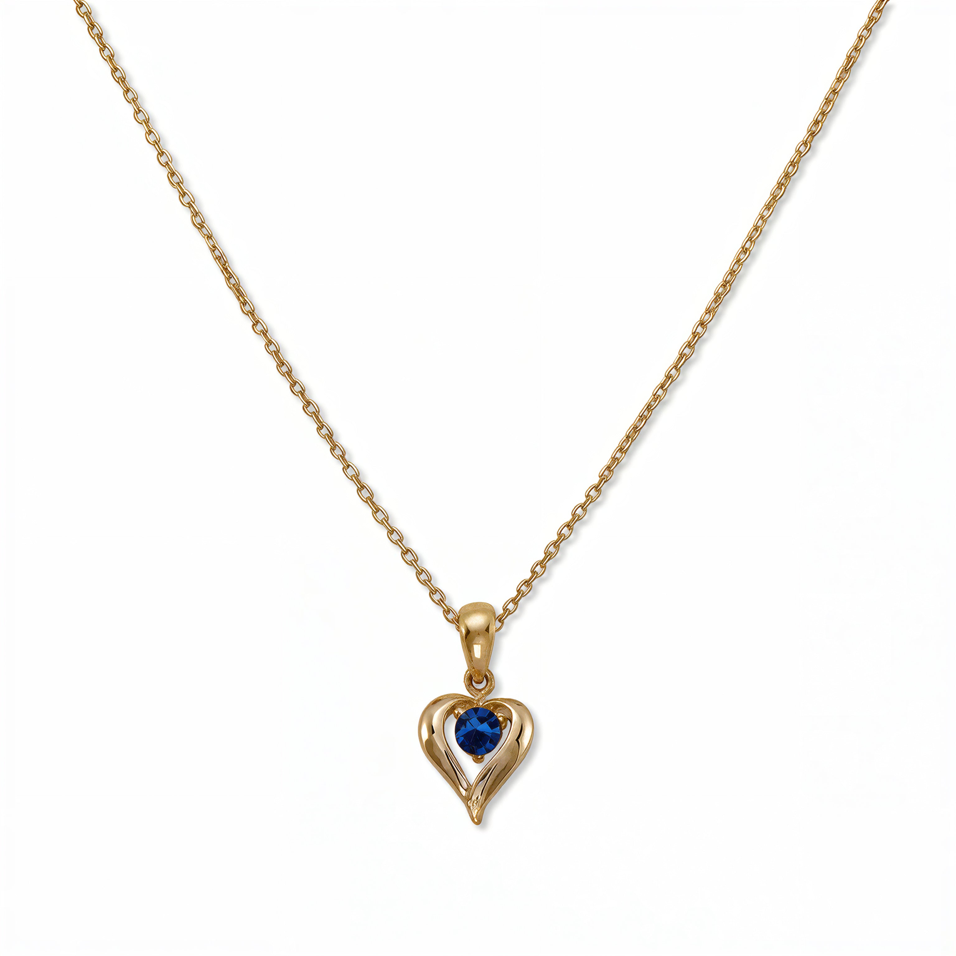 A September Birthstone Sapphire Cubic Zirconia Heart Necklace by Skōsh Jewelry, featuring a heart-shaped deep blue stone framed in a sculpted gold heart pendant on a fine chain, displayed against a white background.