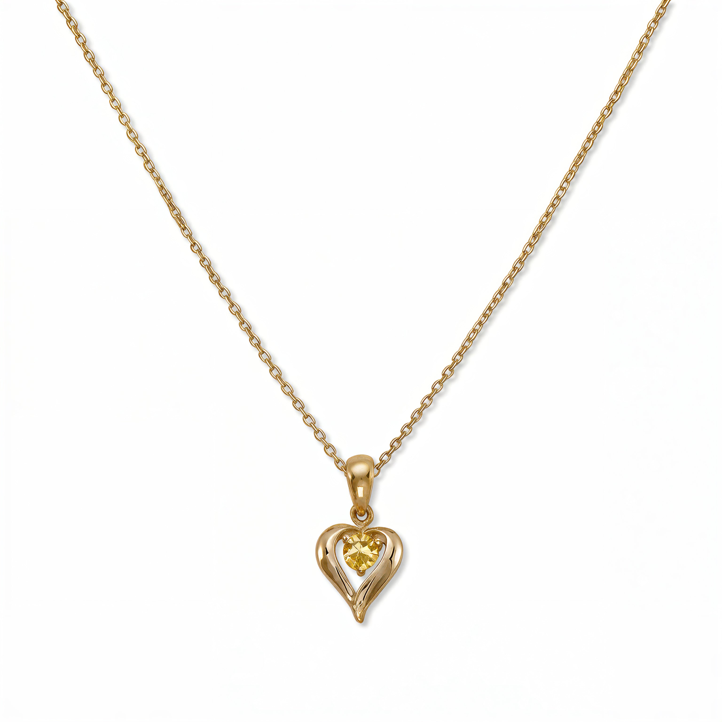A November Birthstone Citrine Cubic Zirconia Heart Necklace by Skōsh Jewelry, featuring a heart-shaped yellow stone framed in a sculpted gold heart pendant on a fine chain, displayed against a white background.