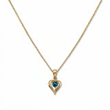 A December Birthstone Aqua Cubic Zirconia Heart Necklace by Skōsh Jewelry, featuring a heart-shaped blue stone framed in a sculpted gold heart pendant on a fine chain, displayed against a white background.