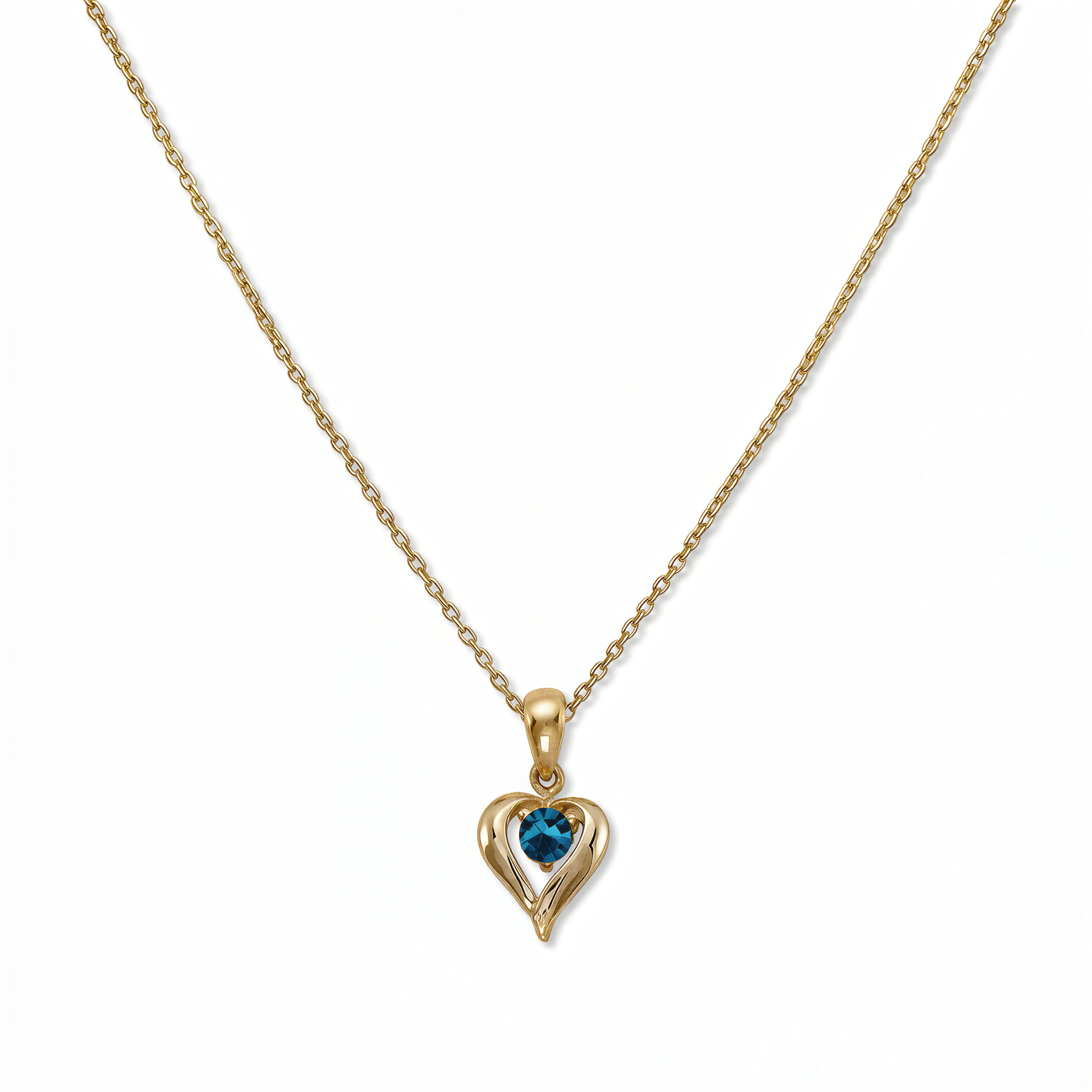 A December Birthstone Aqua Cubic Zirconia Heart Necklace by Skōsh Jewelry, featuring a heart-shaped blue stone framed in a sculpted gold heart pendant on a fine chain, displayed against a white background.