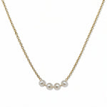 A Skōsh Kids "I'm Four" Petite Freshwater Pearl Necklace by Skōsh Jewelry, featuring four small white freshwater pearls along a fine gold chain, displayed against a white background.