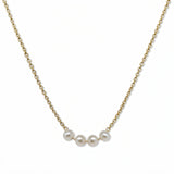 A Skōsh Kids "I'm Four" Petite Freshwater Pearl Necklace by Skōsh Jewelry, featuring four small white freshwater pearls along a fine gold chain, displayed against a white background.