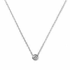 A Stillness Bezel Set White Cubic Zirconia Necklace by Skōsh Jewelry, featuring a single round clear stone in a smooth bezel setting on a fine sterling silver chain, displayed against a white background.