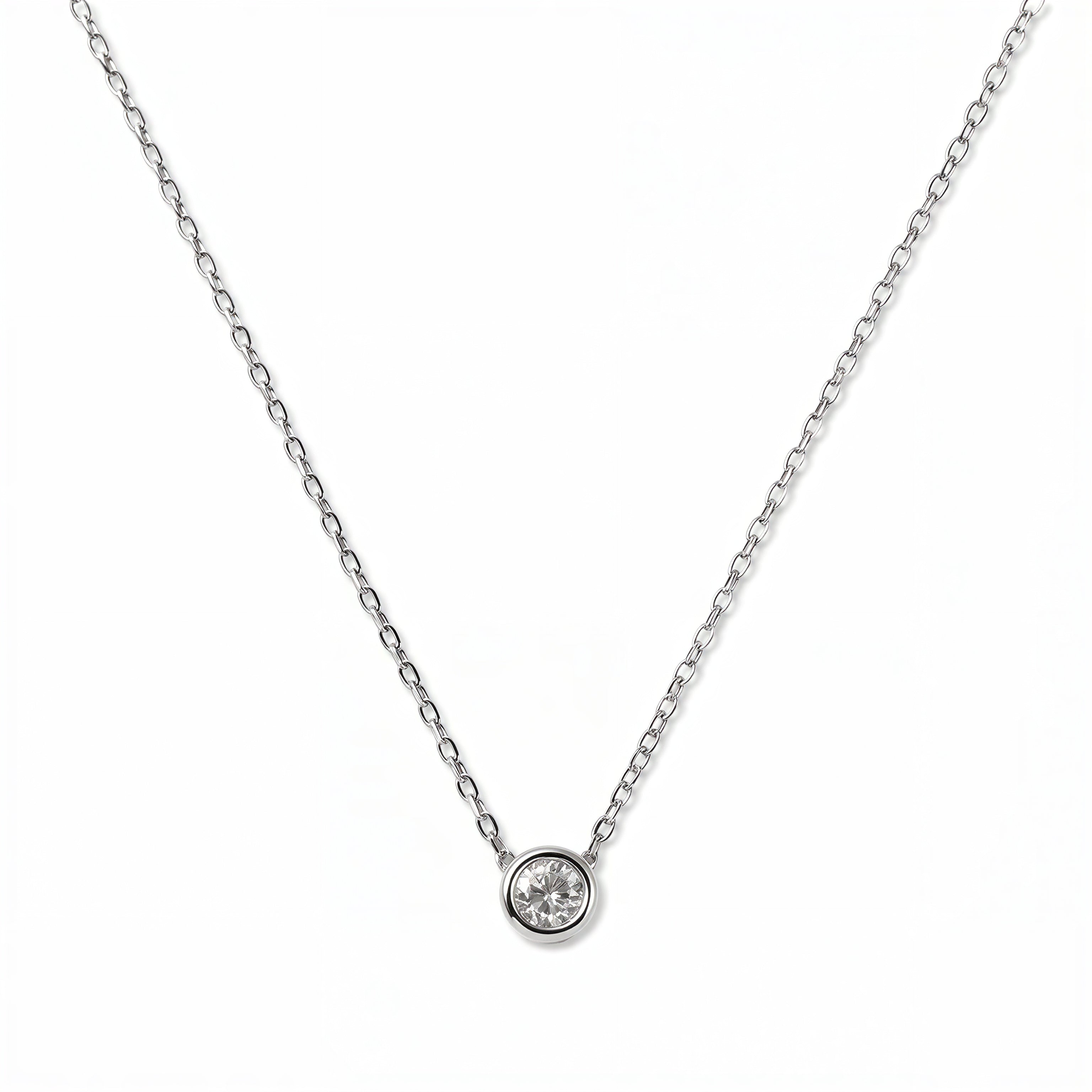 A Stillness Bezel Set White Cubic Zirconia Necklace by Skōsh Jewelry, featuring a single round clear stone in a smooth bezel setting on a fine sterling silver chain, displayed against a white background.
