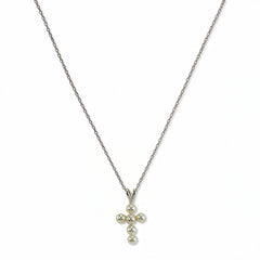 A Blessing Freshwater Pearl Mini Cross Necklace by Skōsh Jewelry, featuring a small cross pendant made of tiny white pearl beads hanging from a fine sterling silver chain, displayed against a white background.