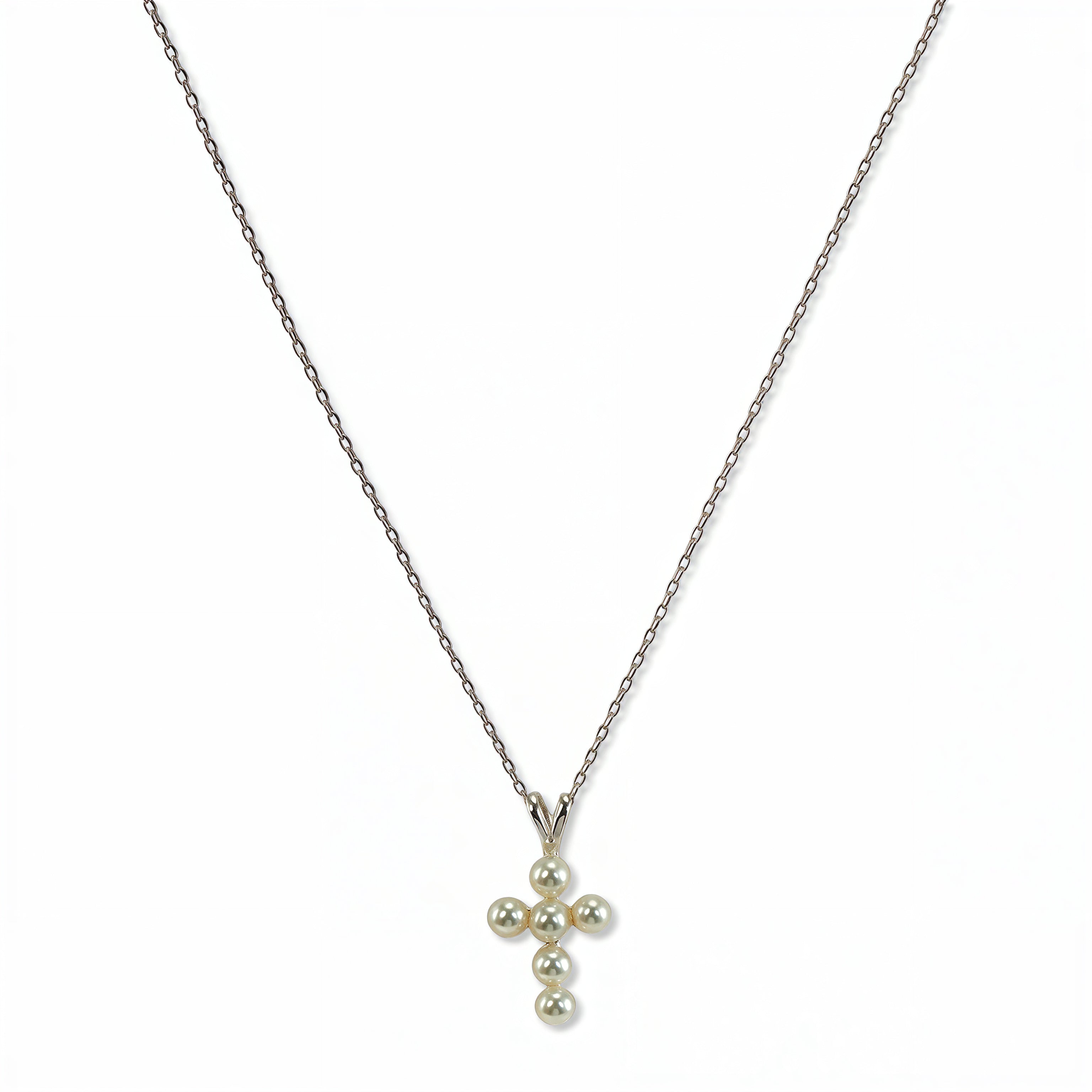 A Blessing Freshwater Pearl Mini Cross Necklace by Skōsh Jewelry, featuring a small cross pendant made of tiny white pearl beads hanging from a fine sterling silver chain, displayed against a white background.