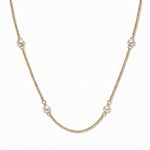 A Nine Station Freshwater Pearl Necklace by Skōsh Jewelry, featuring small white freshwater pearls spaced evenly along a fine gold station chain, displayed against a white background.