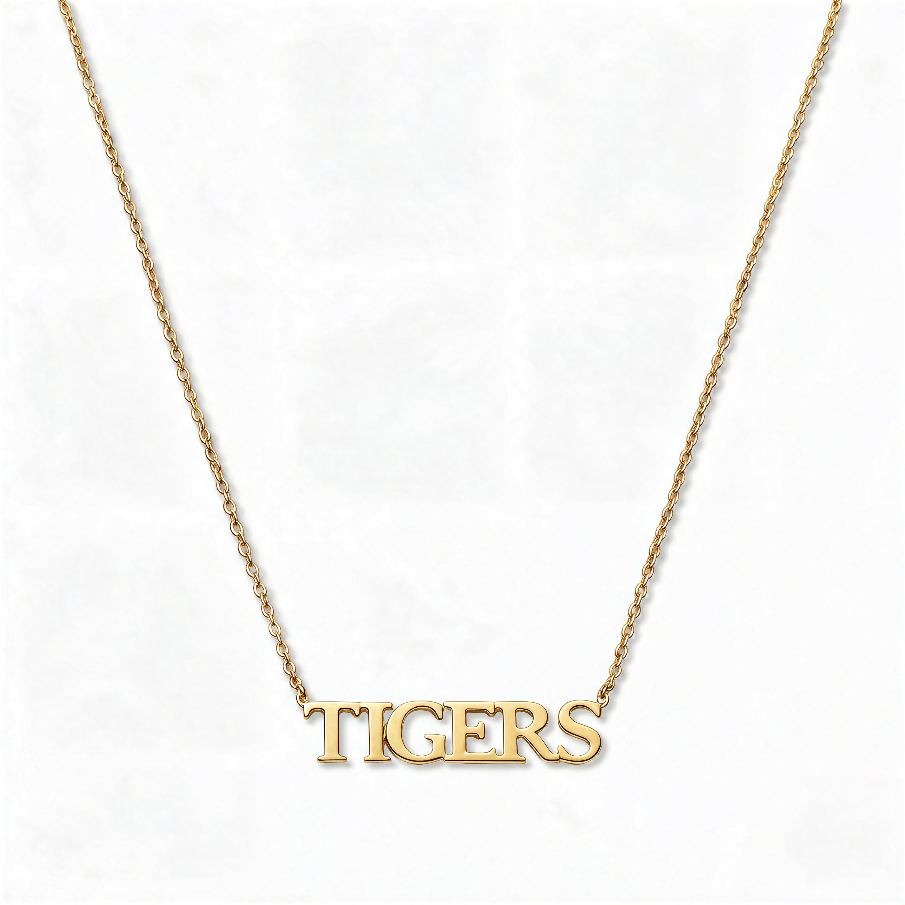 A TIGERS Gameday Necklace by Skōsh Jewelry, featuring the word 'TIGERS' in capital serif letters set horizontally on a fine gold chain, displayed against a white background.