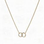 A Friendship Interlocking Circles Necklace by Skōsh Jewelry, featuring two small interlocking circles of equal size on a fine gold chain, displayed against a white background.