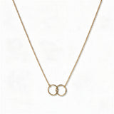 A Friendship Interlocking Circles Necklace by Skōsh Jewelry, featuring two small interlocking circles of equal size on a fine gold chain, displayed against a white background.
