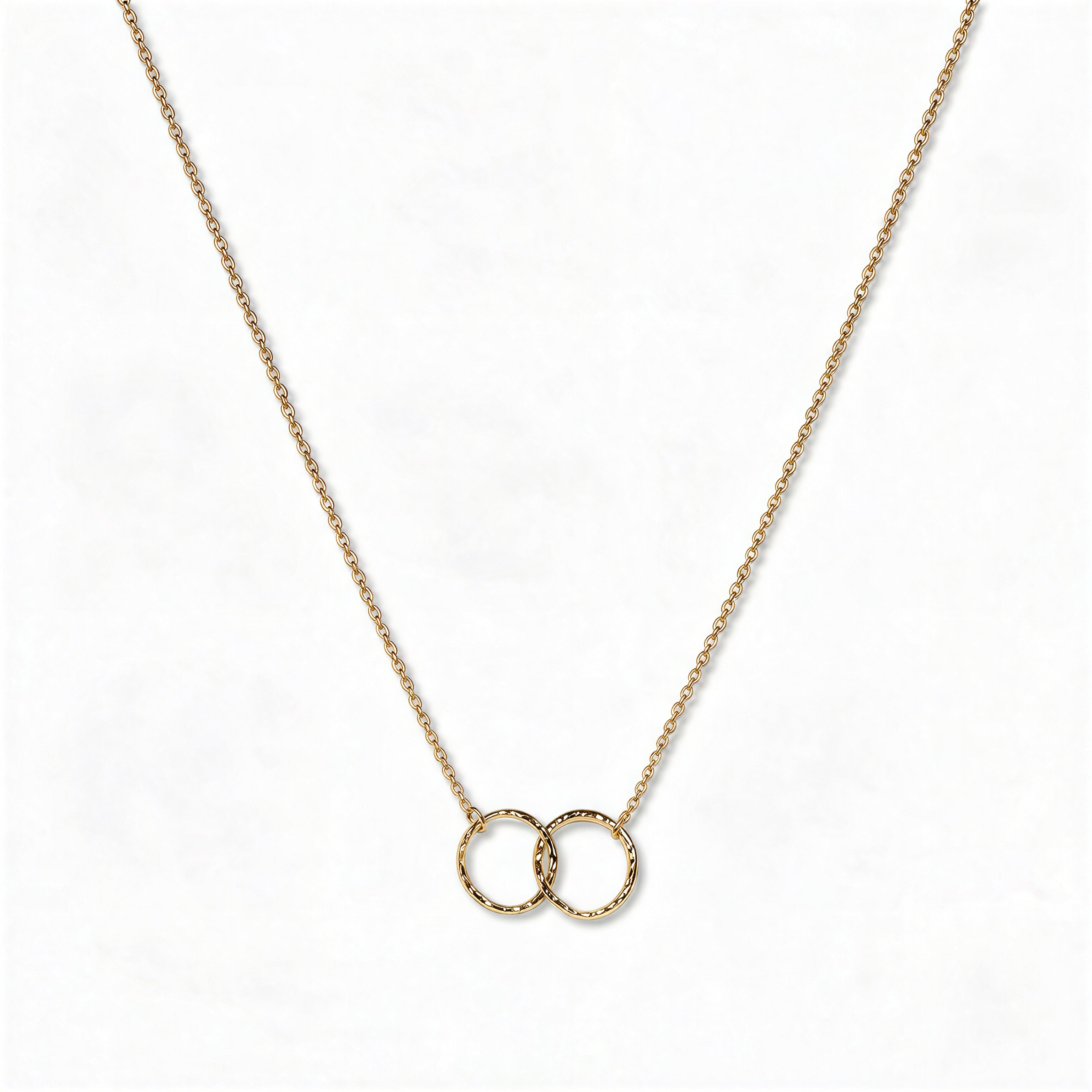 A Friendship Interlocking Circles Necklace by Skōsh Jewelry, featuring two small interlocking circles of equal size on a fine gold chain, displayed against a white background.