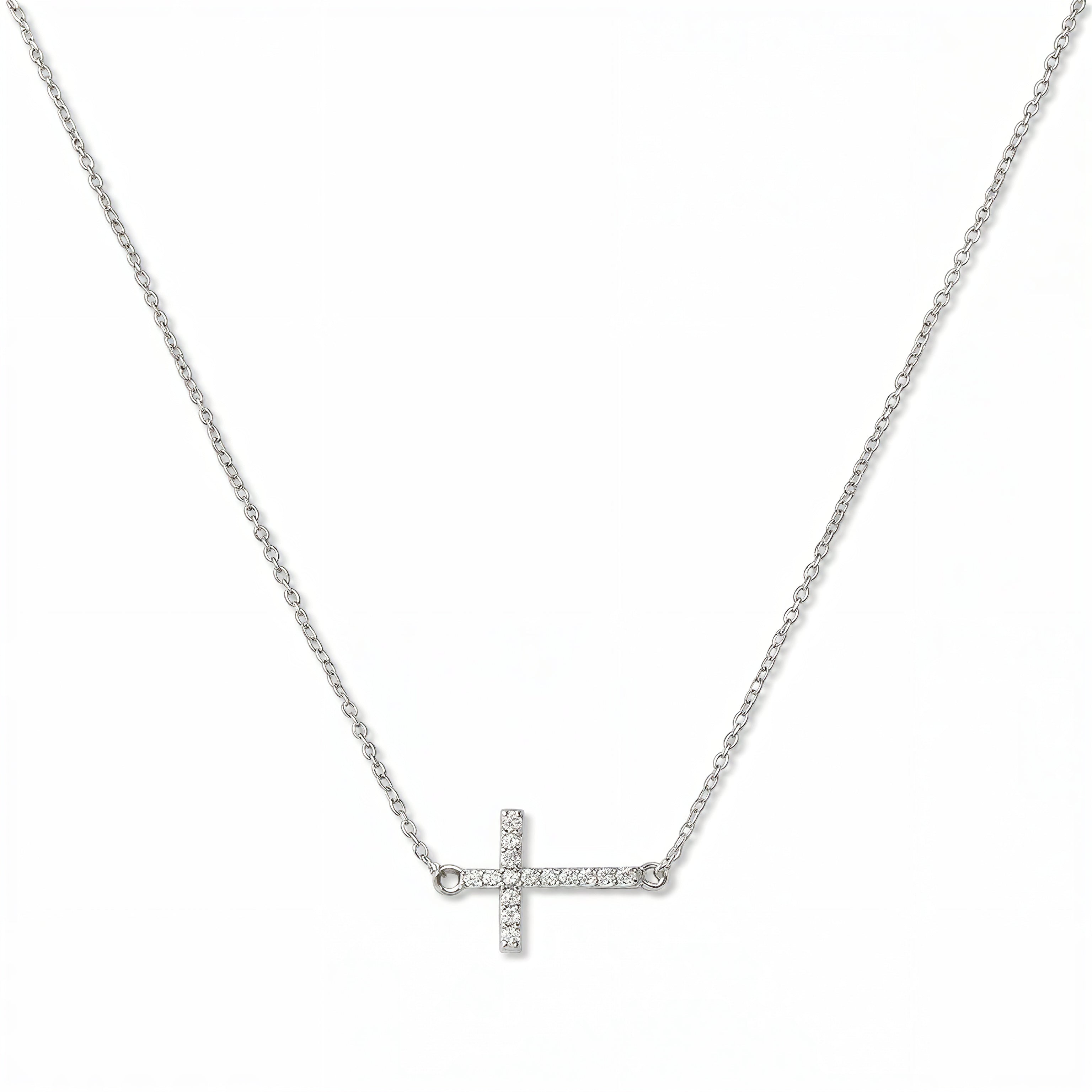 A Devoted White Cubic Zirconia Sideways Cross Necklace by Skōsh Jewelry, featuring a sideways cross lined with small clear pavé stones on a fine sterling silver chain, displayed against a white background.