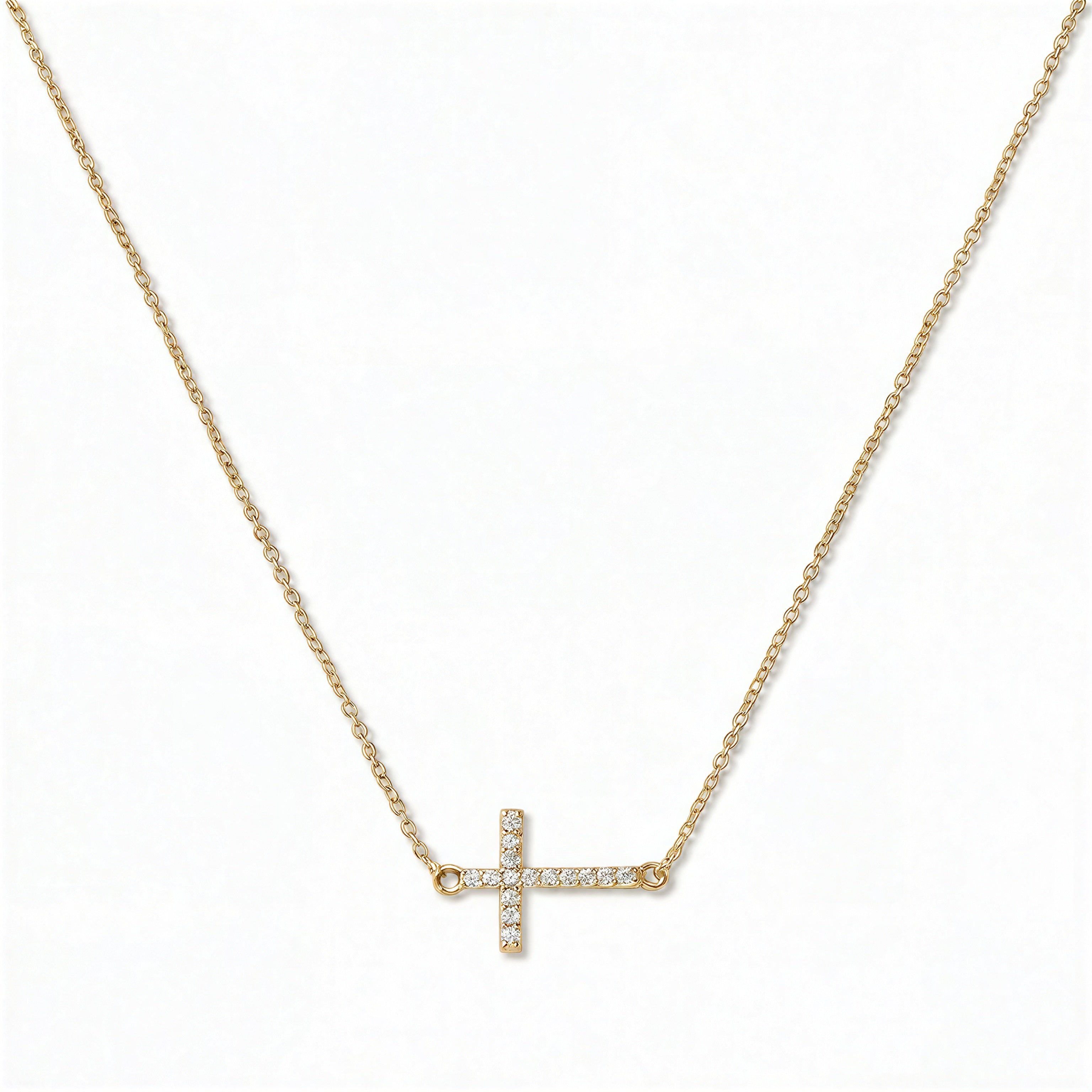 A Devoted White Cubic Zirconia Sideways Cross Necklace by Skōsh Jewelry, featuring a sideways cross lined with small clear pavé stones on a fine gold chain, displayed against a white background.