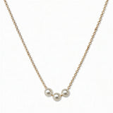 A Timeless Trio Freshwater Pearl Necklace by Skōsh Jewelry, featuring three white freshwater pearls in a row along a fine gold chain, displayed against a white background.
