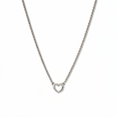 A Lucent Mini Heart Necklace by Skōsh Jewelry, featuring a tiny open heart set on a fine sterling silver chain, displayed against a white background.