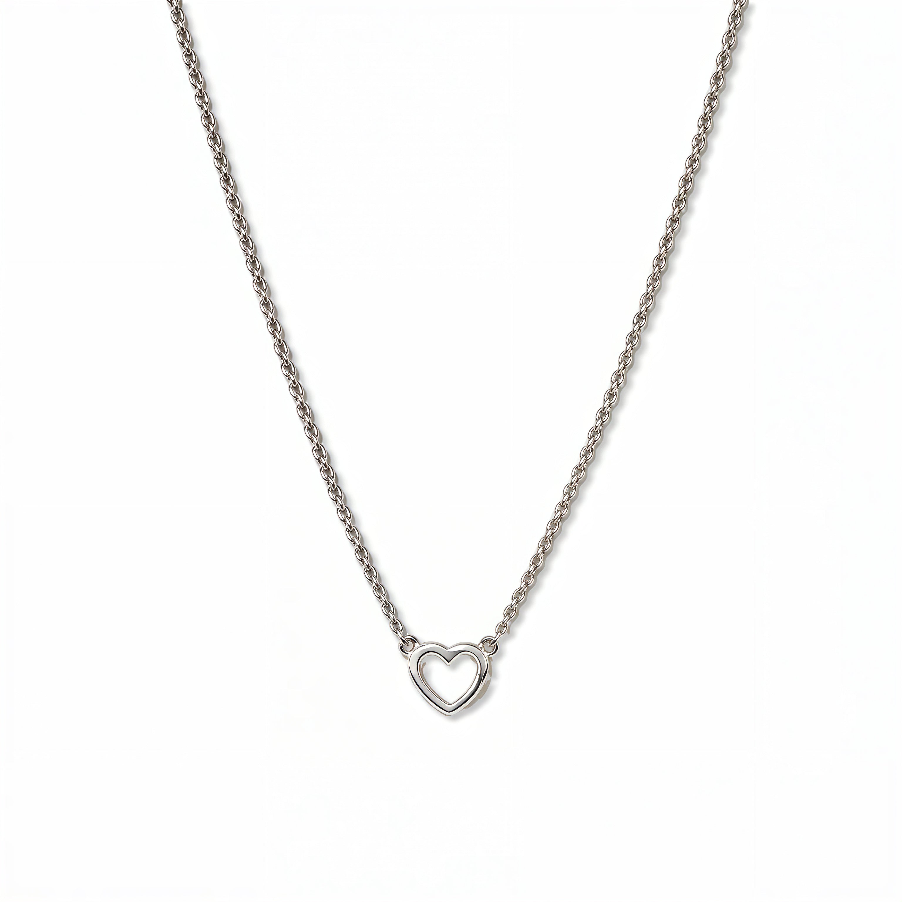 A Lucent Mini Heart Necklace by Skōsh Jewelry, featuring a tiny open heart set on a fine sterling silver chain, displayed against a white background.