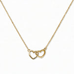 A Forever Love Interlocking Hearts Necklace by Skōsh Jewelry, featuring two open hearts linked together on a fine gold chain, displayed against a white background.