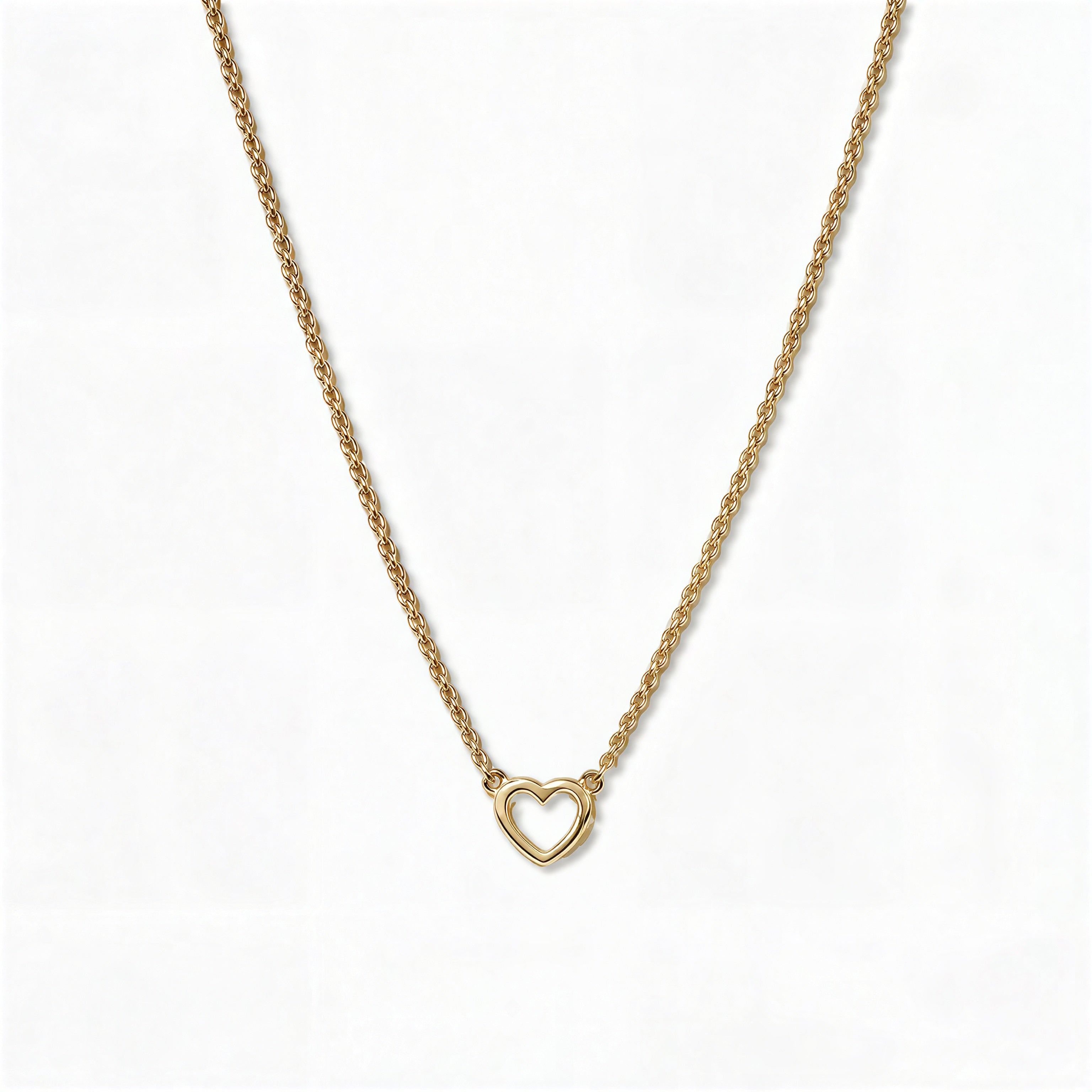 A Lucent Mini Heart Necklace by Skōsh Jewelry, featuring a tiny open heart set on a fine gold chain, displayed against a white background.