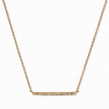 A Luminary White Cubic Zirconia Bar Necklace by Skōsh Jewelry, featuring a long slim bar lined with small clear stones on a fine gold chain, displayed against a white background.