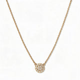 A Luna Glow Pavé Disc White Cubic Zirconia Necklace by Skōsh Jewelry, featuring a round disc covered in small clear pavé stones on a fine gold chain, displayed against a white background.