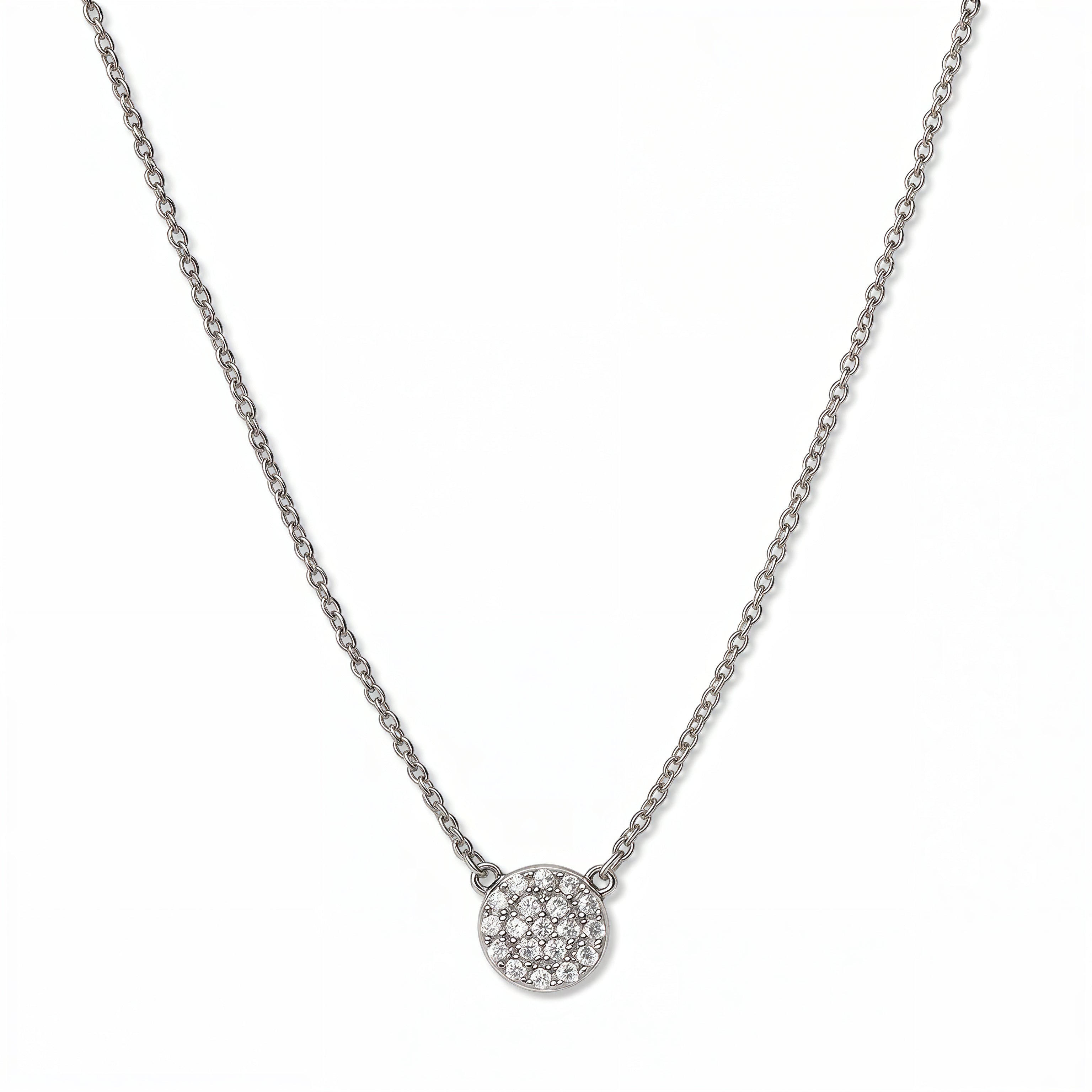 A Luna Glow Pavé Disc White Cubic Zirconia Necklace by Skōsh Jewelry, featuring a round disc covered in small clear pavé stones on a fine sterling silver chain, displayed against a white background.