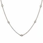 A Starlight Strand Bezel Station White Cubic Zirconia Necklace by Skōsh Jewelry, featuring small round clear stones in bezel settings spaced along a fine sterling silver chain, displayed against a white background.