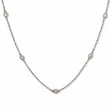 A Starlight Strand Bezel Station White Cubic Zirconia Necklace by Skōsh Jewelry, featuring small round clear stones in bezel settings spaced along a fine sterling silver chain, displayed against a white background.