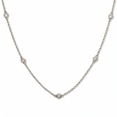 A Starlight Strand Bezel Station White Cubic Zirconia Necklace by Skōsh Jewelry, featuring small round clear stones in bezel settings spaced along a fine sterling silver chain, displayed against a white background.