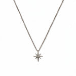 A North Star White Cubic Zirconia Accent Pendant Necklace by Skōsh Jewelry, featuring an eight-point star pendant with a small clear stone at its center on a fine sterling silver chain, displayed against a white background.
