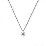 A North Star White Cubic Zirconia Accent Pendant Necklace by Skōsh Jewelry, featuring an eight-point star pendant with a small clear stone at its center on a fine sterling silver chain, displayed against a white background.
