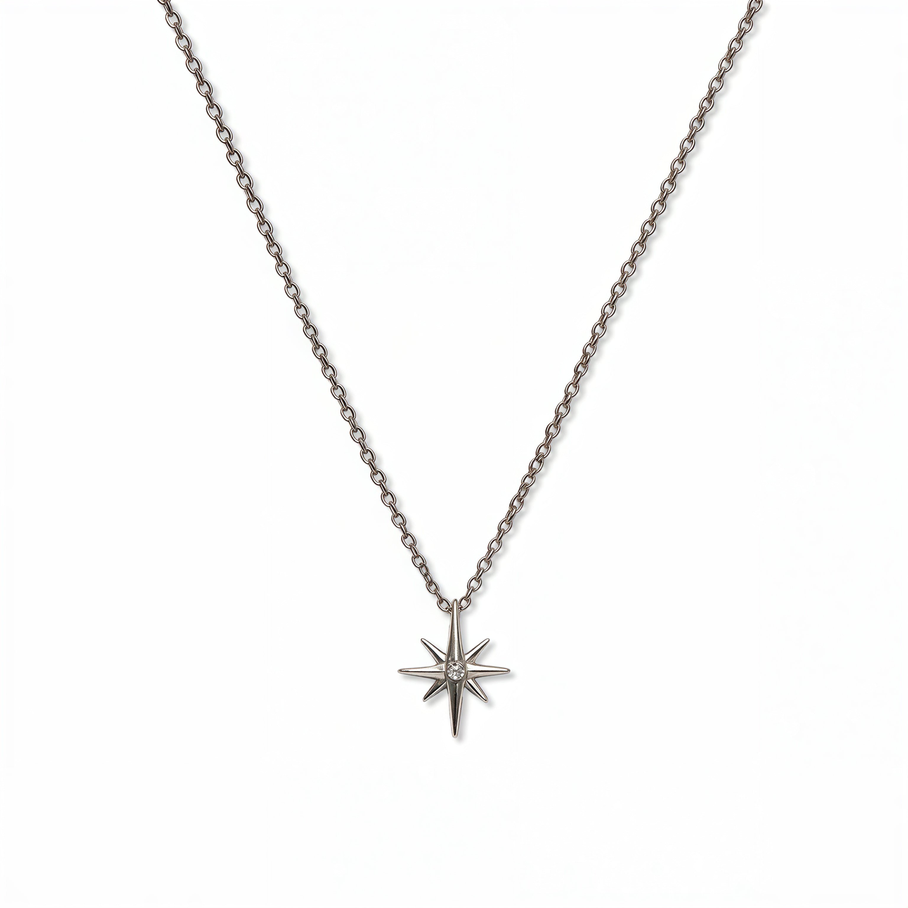 A North Star White Cubic Zirconia Accent Pendant Necklace by Skōsh Jewelry, featuring an eight-point star pendant with a small clear stone at its center on a fine sterling silver chain, displayed against a white background.