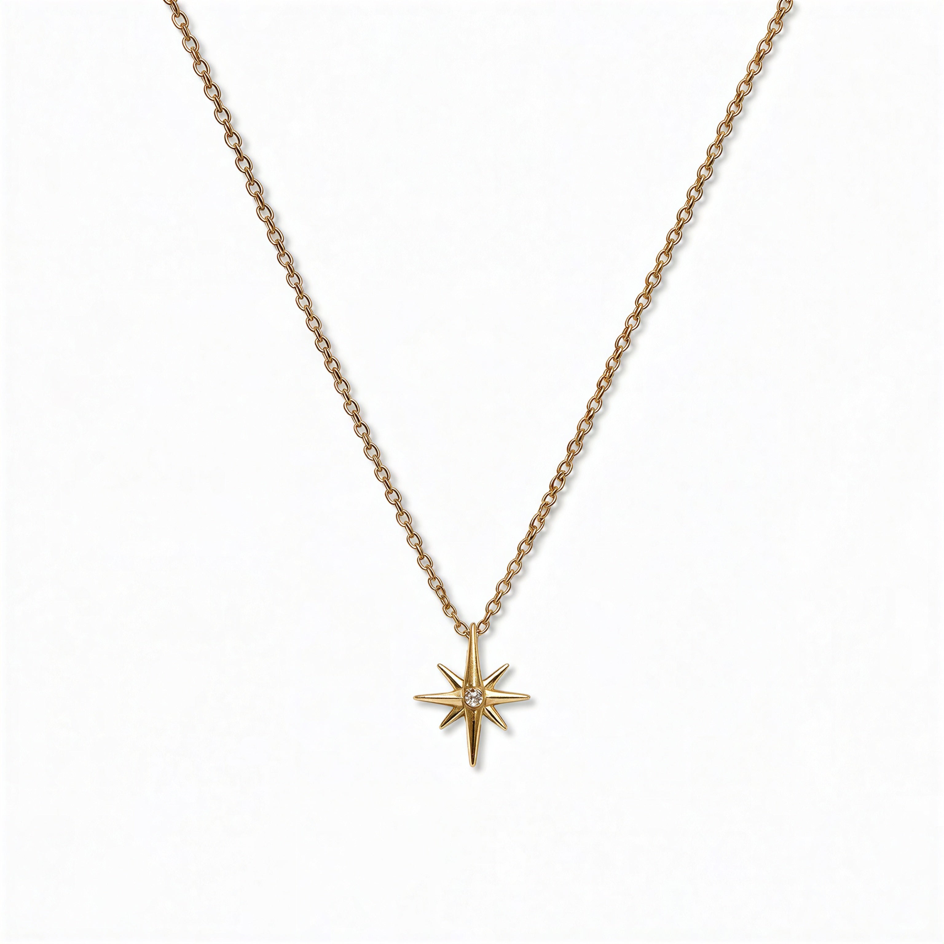 A North Star White Cubic Zirconia Accent Pendant Necklace by Skōsh Jewelry, featuring an eight-point star pendant with a small clear stone at its center on a fine gold chain, displayed against a white background.