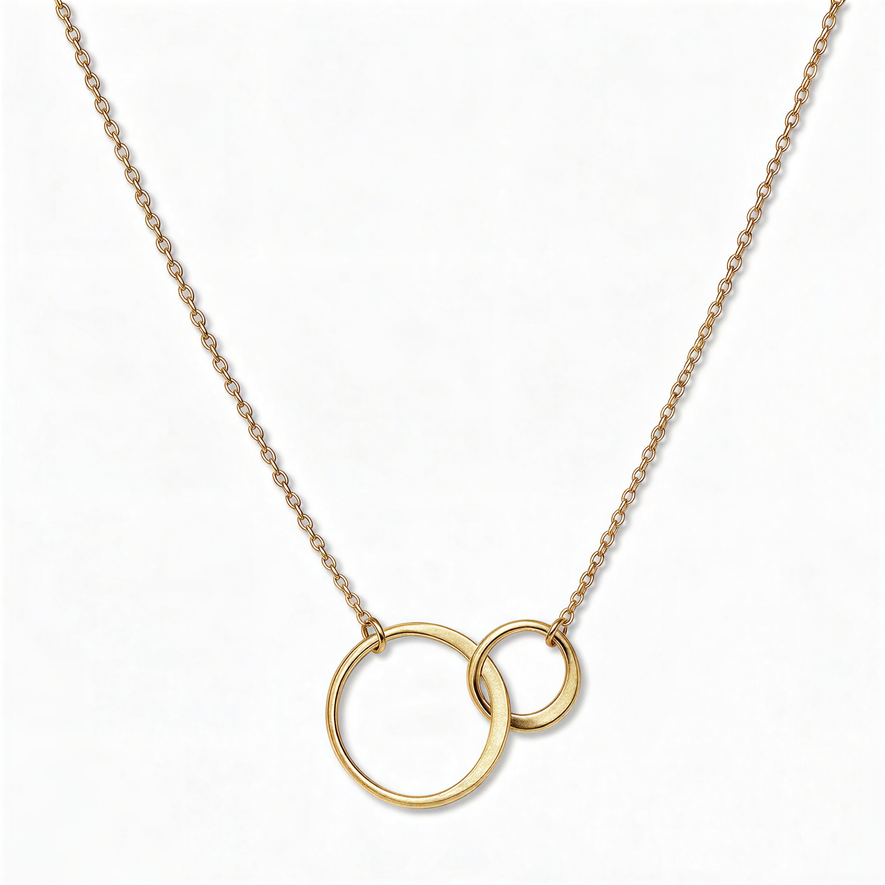 A Held Close Mother and Daughter Circles Necklace by Skōsh Jewelry, featuring one large and one small open circle linked together on a fine gold chain, displayed against a white background.