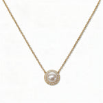 A Freshwater Pearl with White Cubic Zirconia Halo Necklace by Skōsh Jewelry, featuring a round white freshwater pearl surrounded by a halo of small clear stones on a fine gold chain, displayed against a white background.