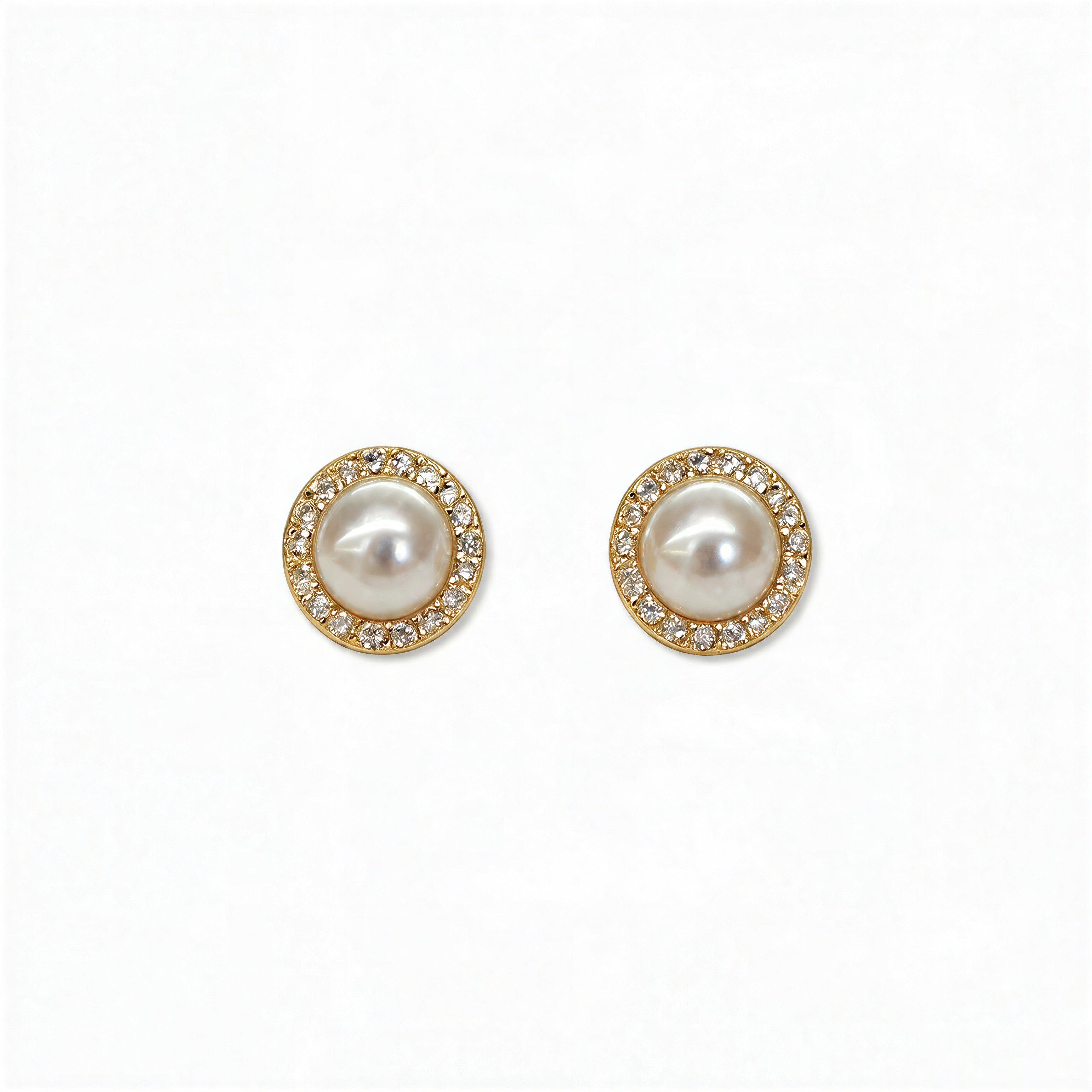 A pair of Freshwater Pearl with White Cubic Zirconia Halo Earrings by Skōsh Jewelry, featuring round white freshwater pearls framed by halos of small clear stones in gold, displayed against a white background.
