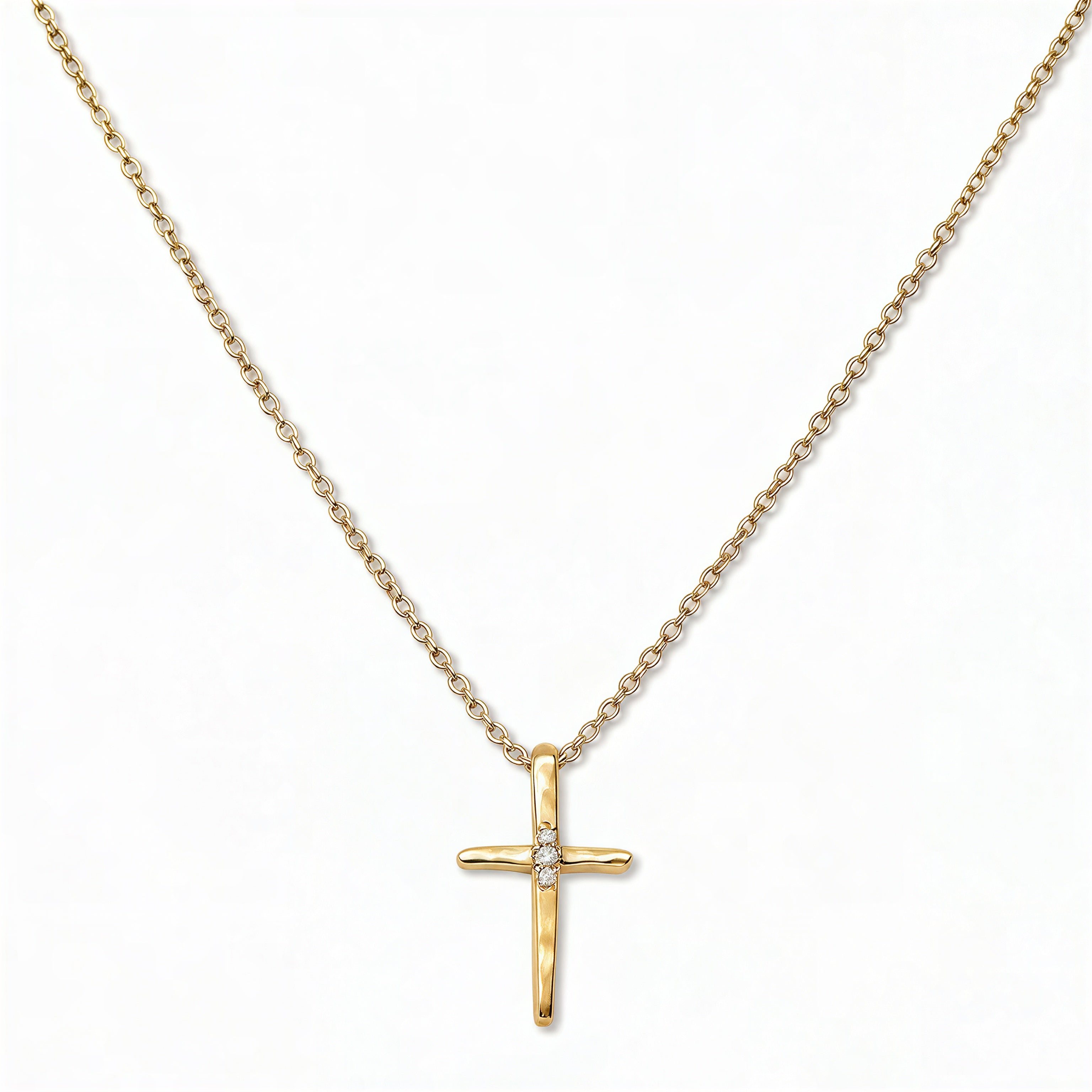A Redemption Hammered Cross with White Cubic Zirconia Necklace by Skōsh Jewelry, featuring a hammered cross accented with three small clear stones on a fine gold chain, displayed against a white background.