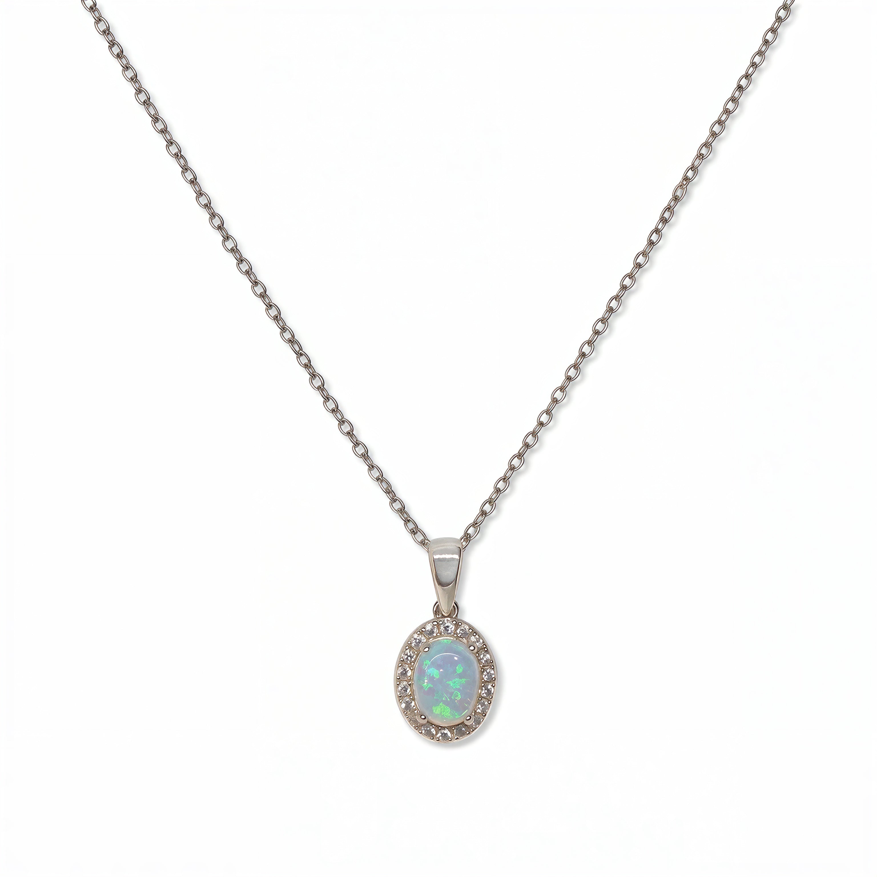 An Ethereal Opal with White Cubic Zirconia Halo Pendant Necklace by Skōsh Jewelry, featuring an oval iridescent opal framed by a halo of small clear stones on a fine sterling silver chain, displayed against a white background.