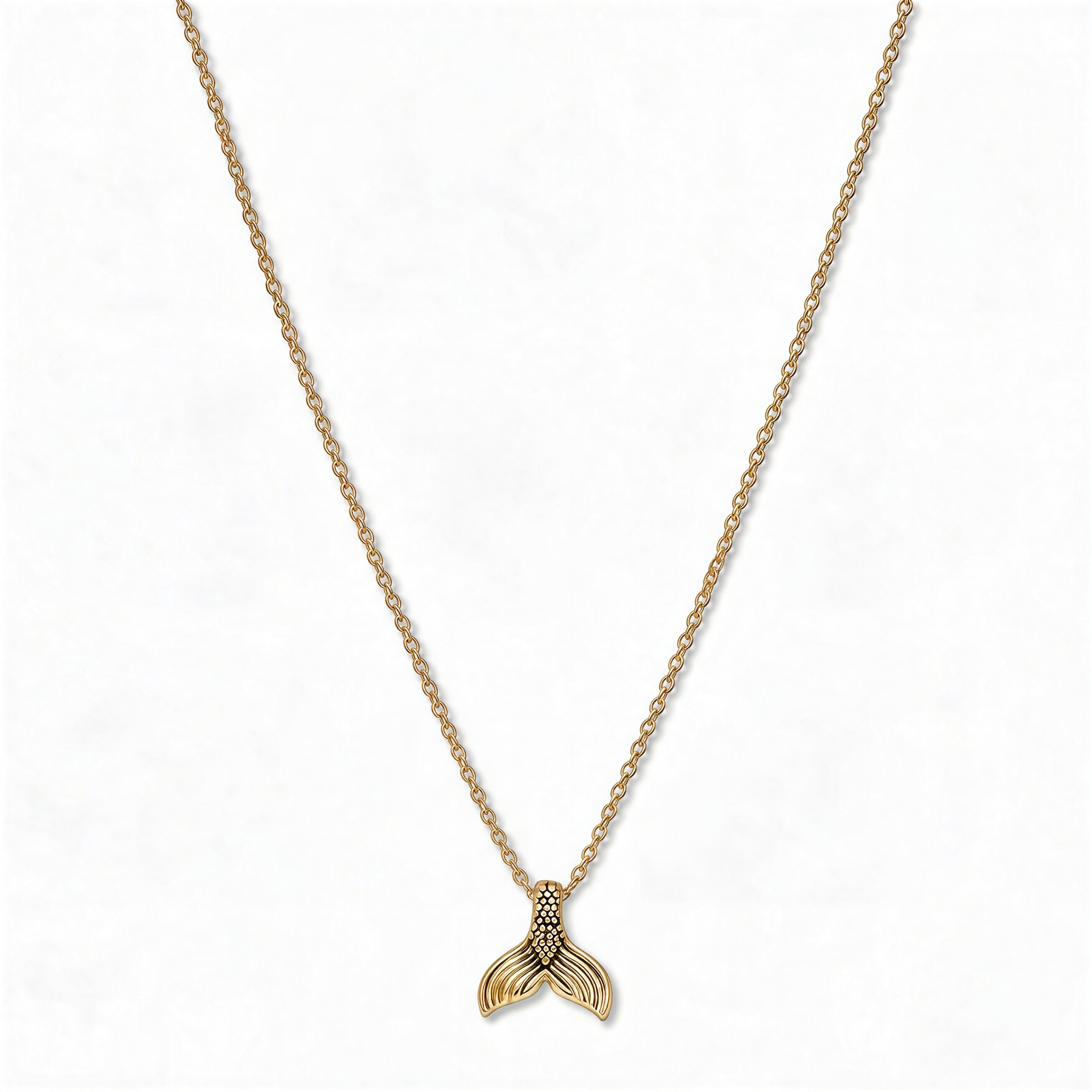 A Mermaid Tail Pendant Necklace by Skōsh Jewelry, featuring a small textured mermaid tail pendant on a fine gold chain, displayed against a white background.