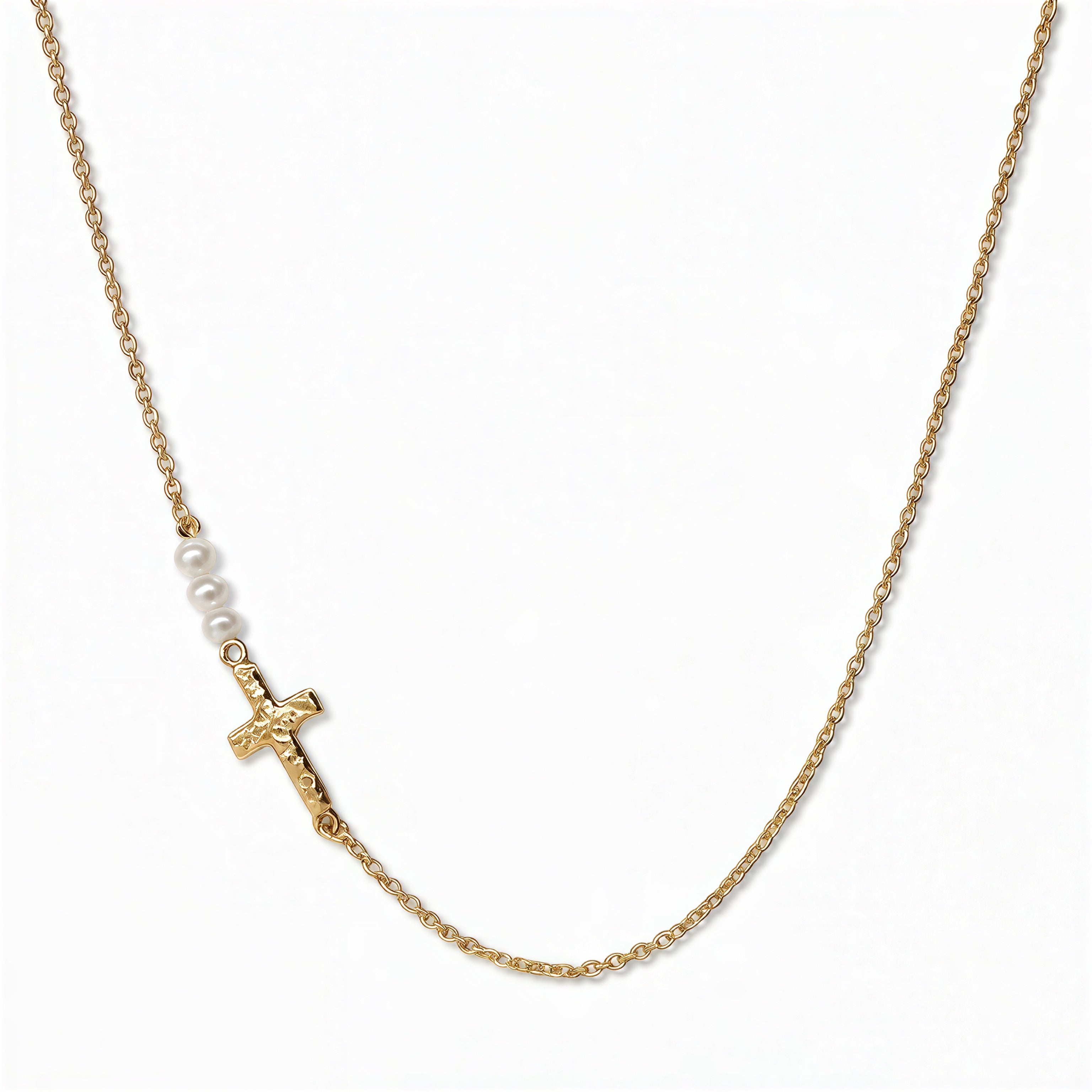 A Promise Inline Cross with Pearl Accent Necklace by Skōsh Jewelry, featuring a sideways cross formed from small white pearls on a fine gold chain, displayed against a white background.