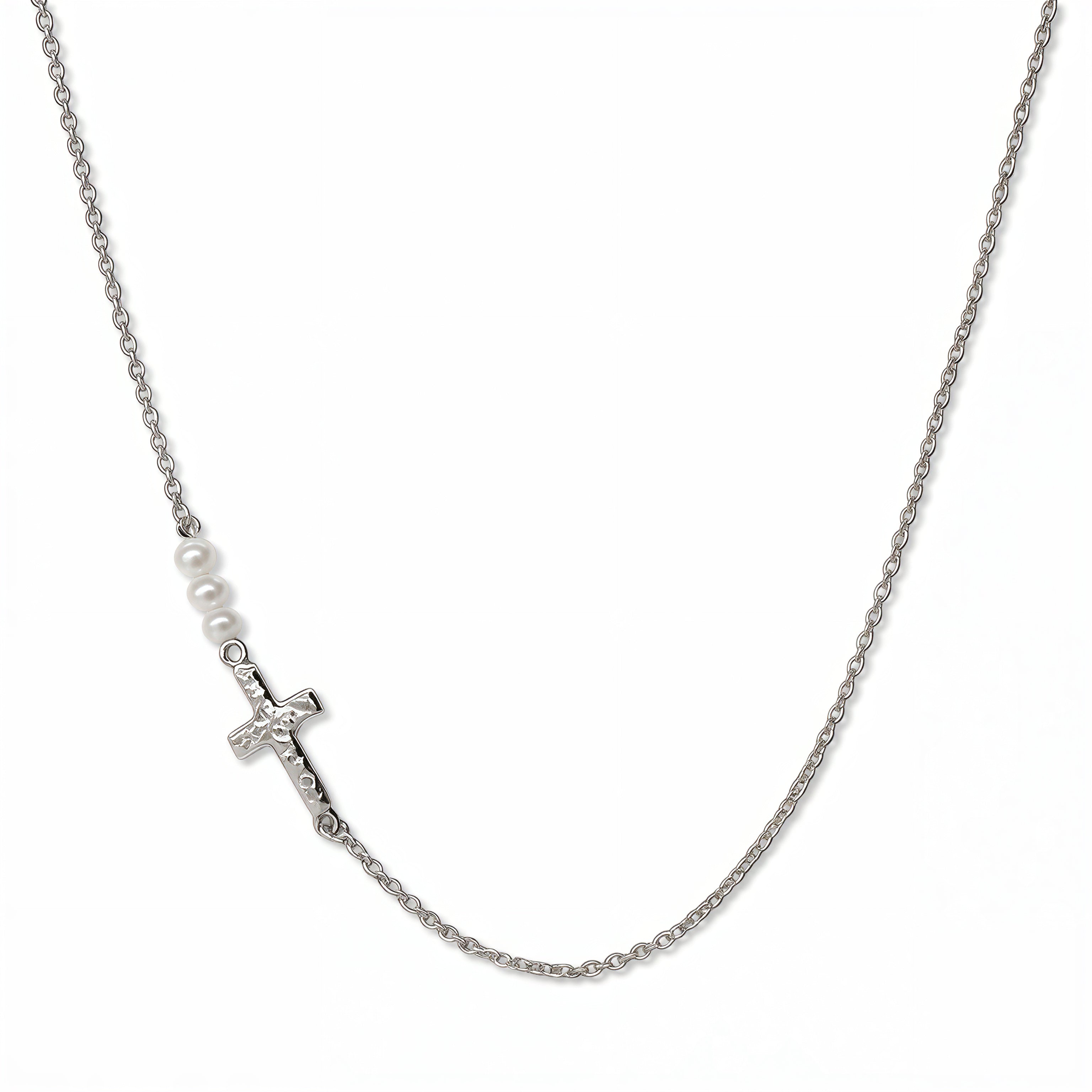 A Promise Inline Cross with Pearl Accent Necklace by Skōsh Jewelry, featuring a sideways cross formed from small white pearls on a fine sterling silver chain, displayed against a white background.